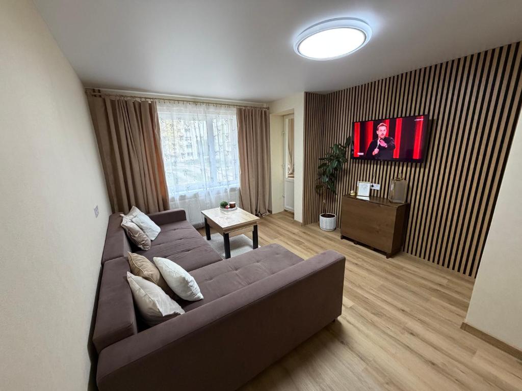 a living room with a couch and a tv at Harmony Apartments Lux in Liepāja