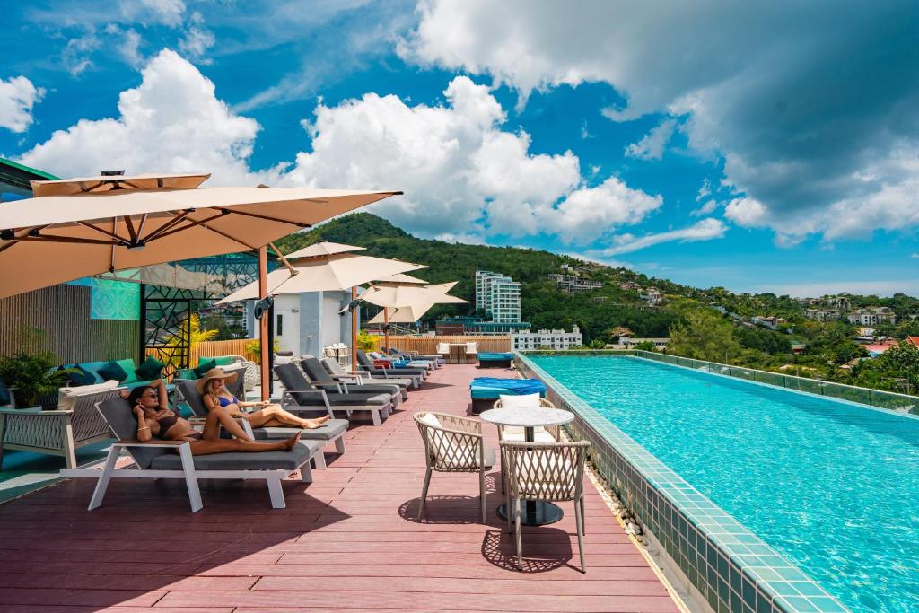 a pool at a hotel with two women sitting on chairs next to it at Ratana Platinum Resort Kamala in Kamala Beach
