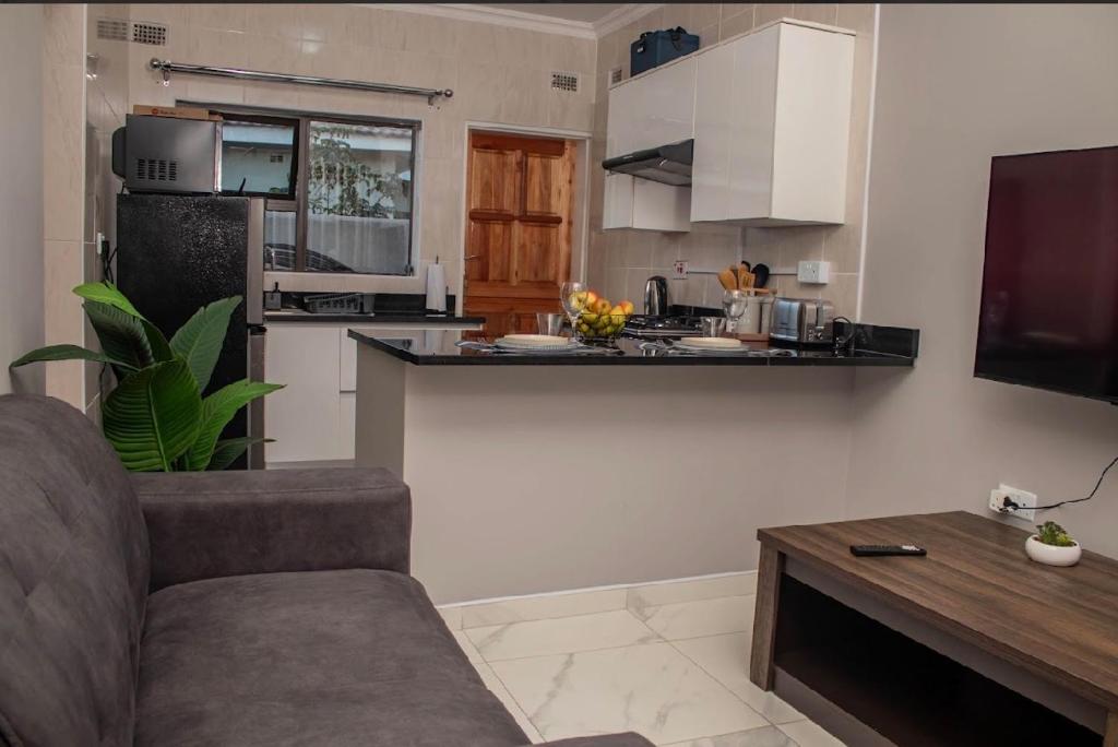 a living room with a couch and a kitchen at MbaliBliss at Selborne in Bulawayo