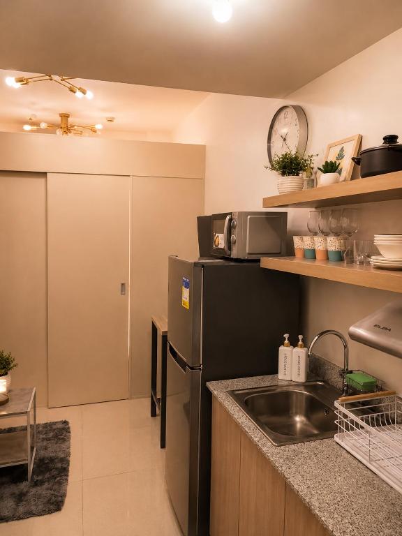 a kitchen with a black refrigerator and a sink at Stylish 1BR Condo @ SM Southmall in Manila