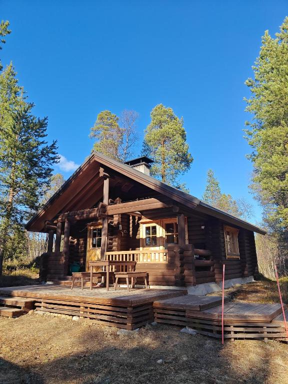 a log cabin with a large deck in the woods at Kotikolo in Inari