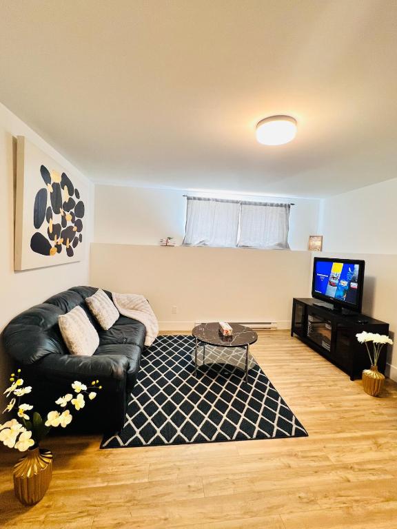 a living room with a black leather couch and a tv at New & Modern Suite in Bristol Riverview in Riverview