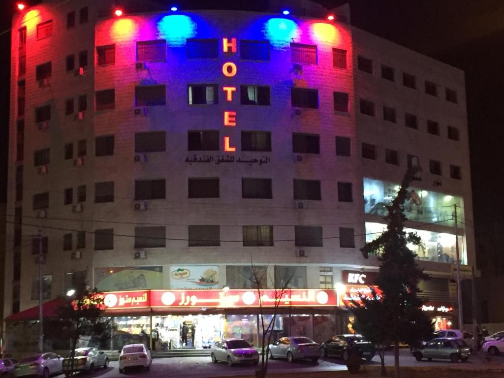 a building with red and blue lights on it at Al Tawheed Hotel Apartments in Amman