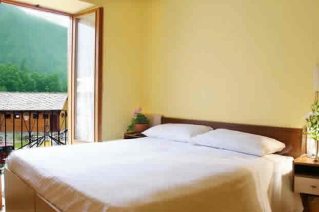 a bedroom with a large white bed and a window at Hotel Grand Usseglio in Usseglio