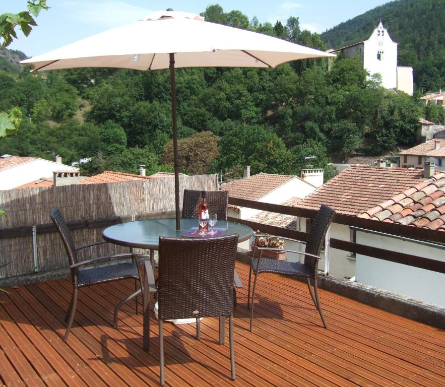 La Maison في Axat: طاولة وكراسي مع مظلة على السطح