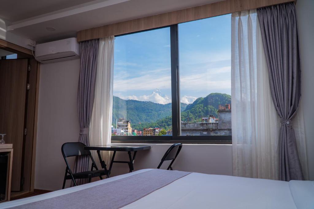 a bedroom with a bed and a large window at Hotel Sampada Boutique in Pokhara