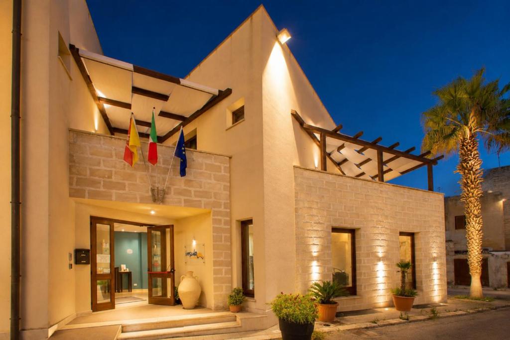 ein Gebäude mit einer Palme davor in der Unterkunft Insula Hotel in Favignana