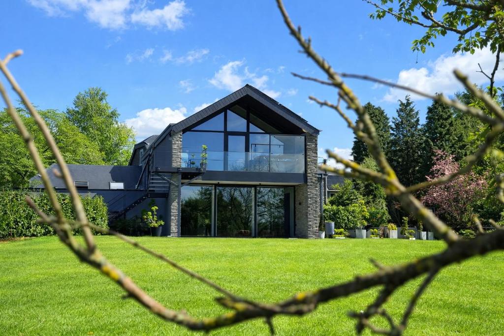 a house with glass windows on a lawn at Lodge Osciade in Sibret