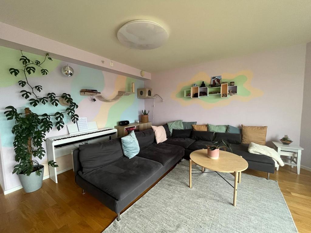 a living room with a black couch and a piano at Spacious apartment with amazing views in Sandnes