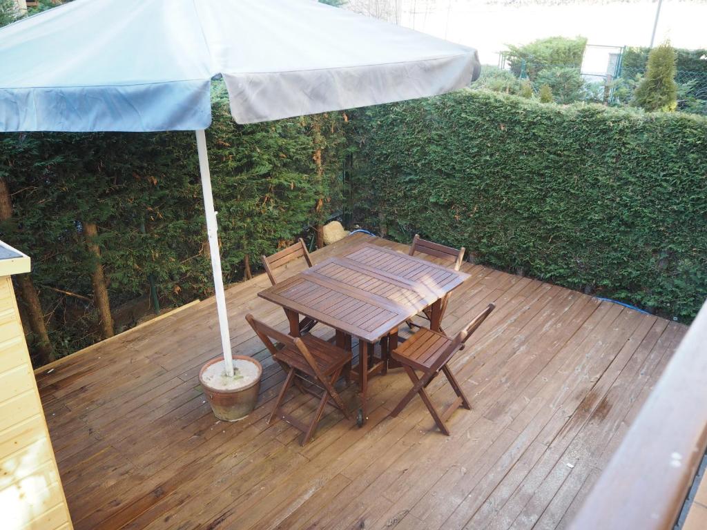 a wooden table and chairs under an umbrella on a deck at Watching Vilallonga de Ter in Vilallonga de Ter