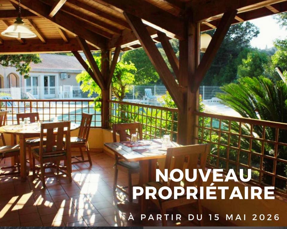a patio with a wooden pergola with tables and chairs at Hostellerie Saint Benoît in Aniane