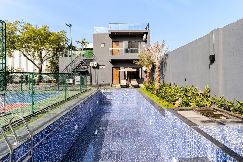 a swimming pool with a tennis court in front of a building at HomeGround Sector 89 -1RK in Gurgaon