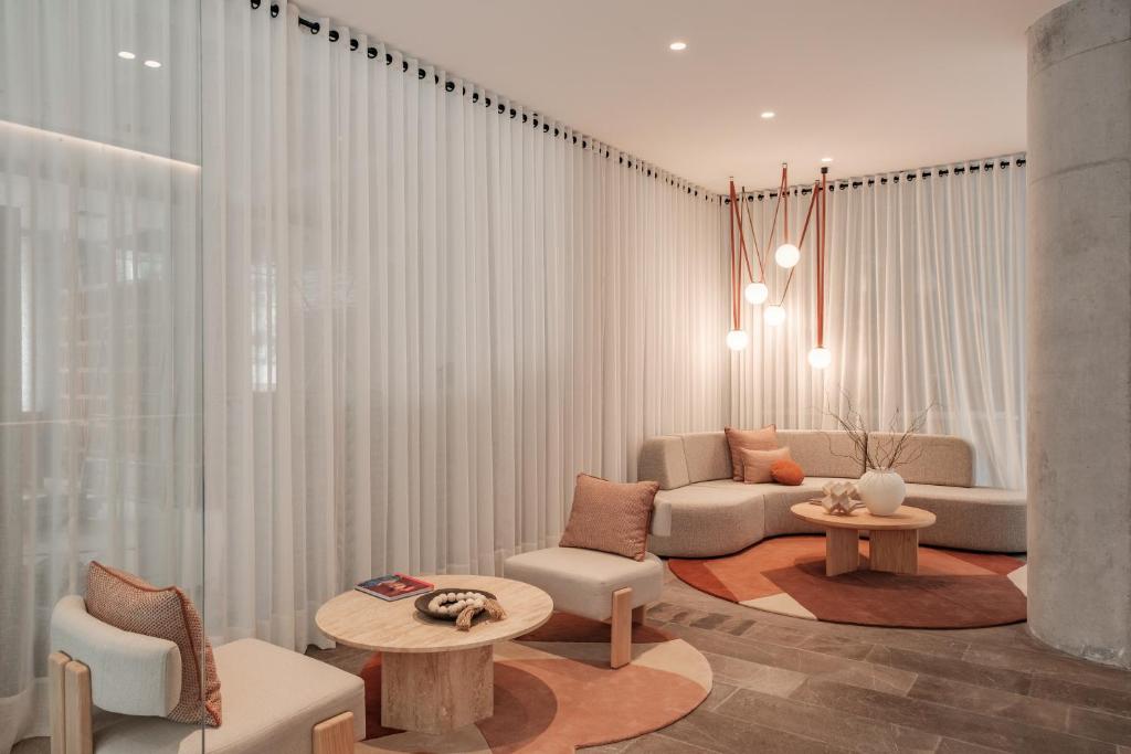 a living room with white curtains and a couch at Nomu Mexico City by Lumina in Mexico City