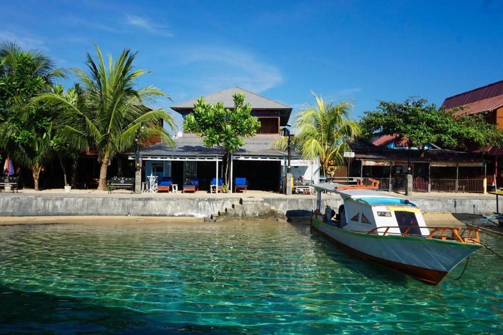 a boat sitting in the water next to a building at 4 Sisters Divers in Bunaken