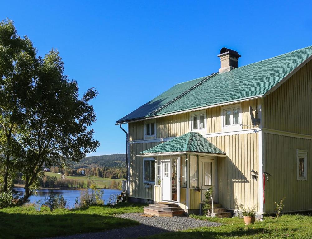 a large green barn with a green roof at Lakeside House, Storstugan in Ramvik