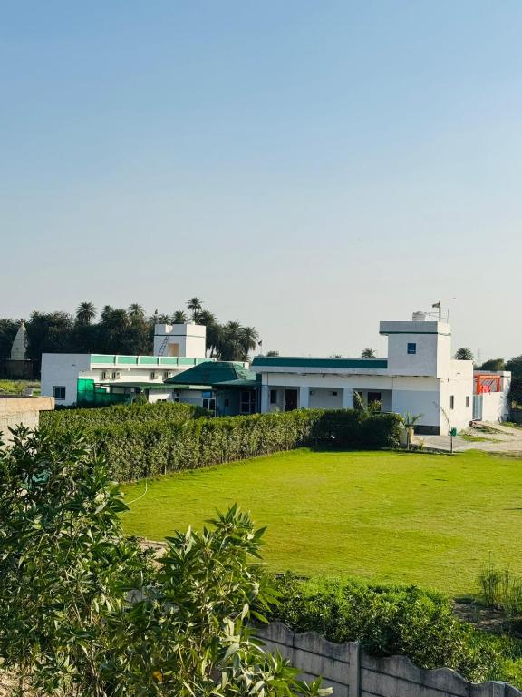 a building with a green field in front of it at Mangalm Farm & Resort in Greater Noida