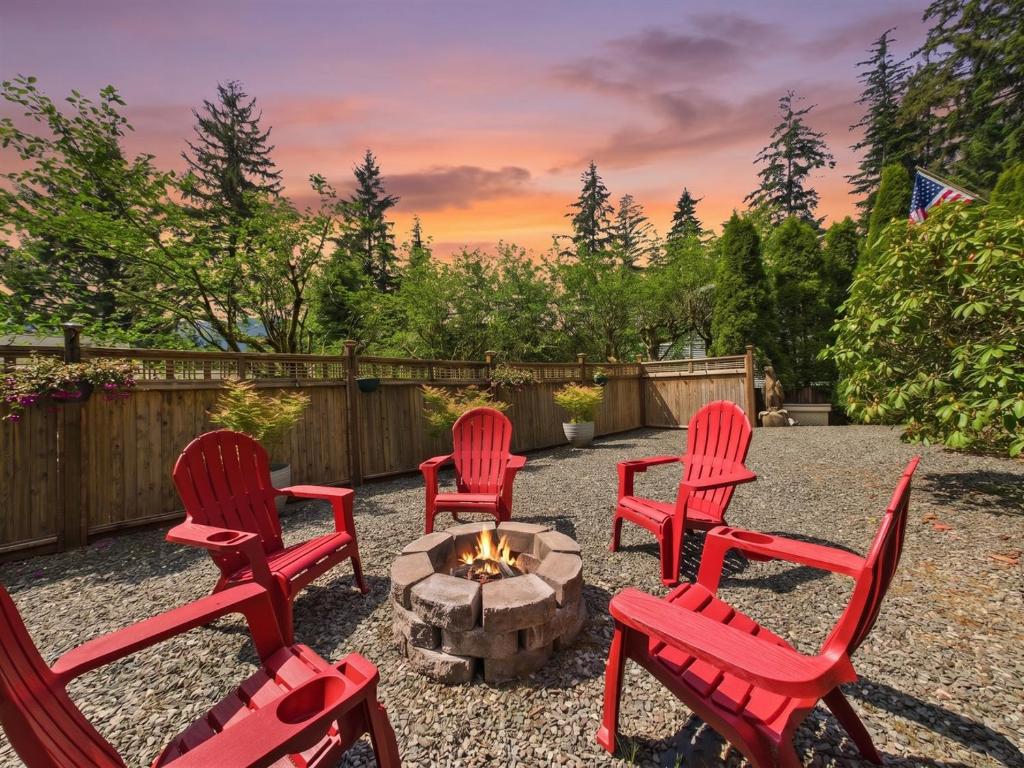 a group of red chairs around a fire pit at Treetop Retreat w Fire Pit in Juneau