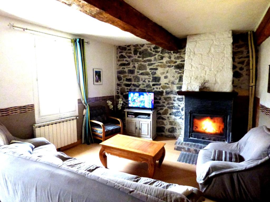 sala de estar con chimenea de piedra y sofá en Gîte Les Mimosas en Prugnanes
