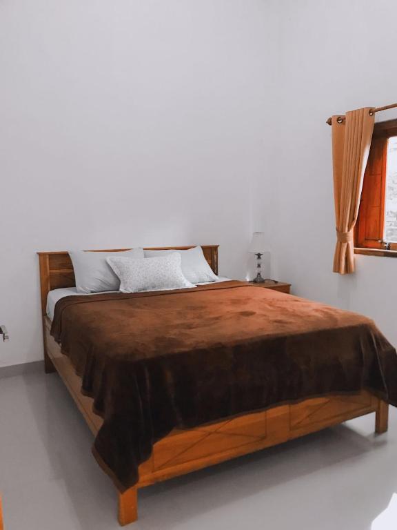 a bedroom with a large wooden bed in a room at Anorawi surf accommodation in Maluk
