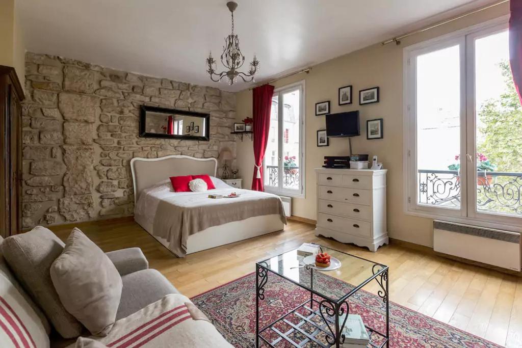 - une chambre avec un lit et un mur en pierre dans l'établissement Studio Saint Louis en Ile, à Paris