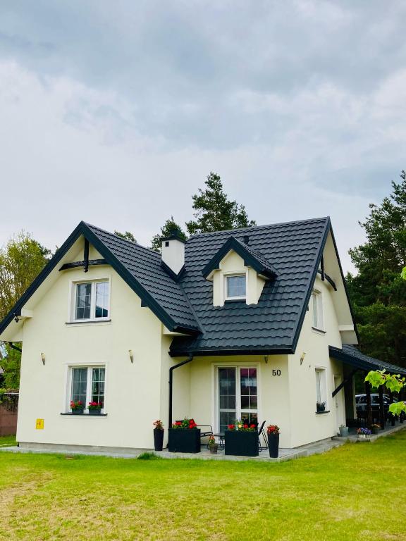 a white house with a black roof at Agroturystyka u Sylwii in Majdan Sopocki
