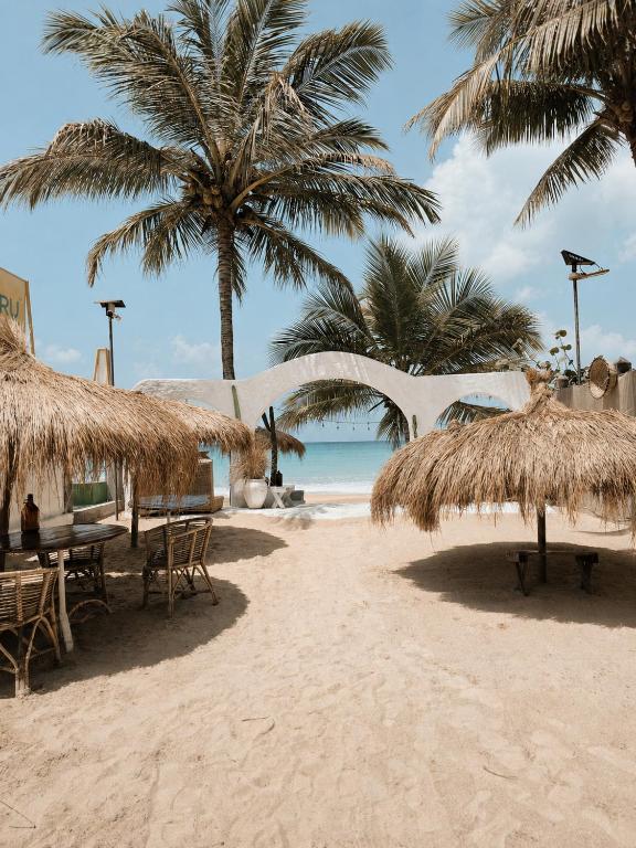 a beach with tables and palm trees and the ocean at Memo's Beach in Nilaveli