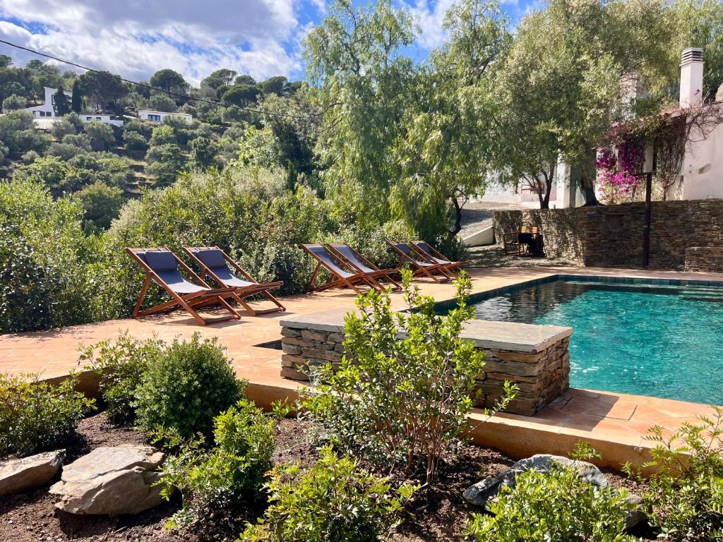 a swimming pool with lounge chairs next to a house at Ses Terrasses in Cadaqués