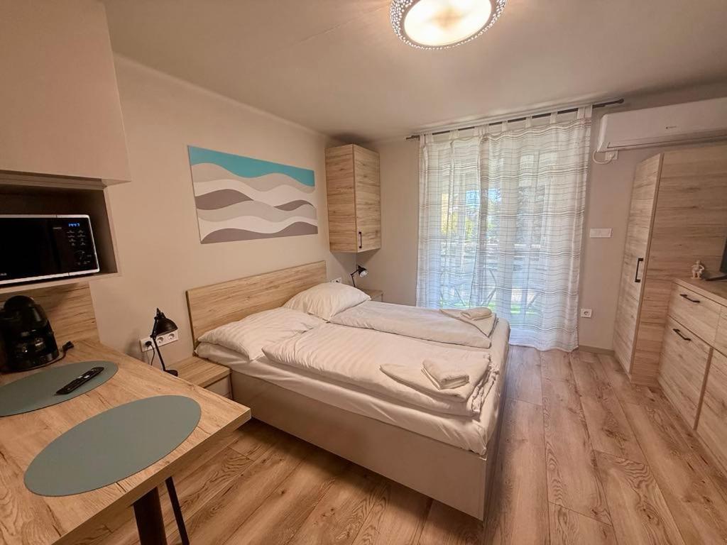 a bedroom with a bed and a desk and a window at Nautica Stúdió by HelloBalatonlelle in Balatonlelle