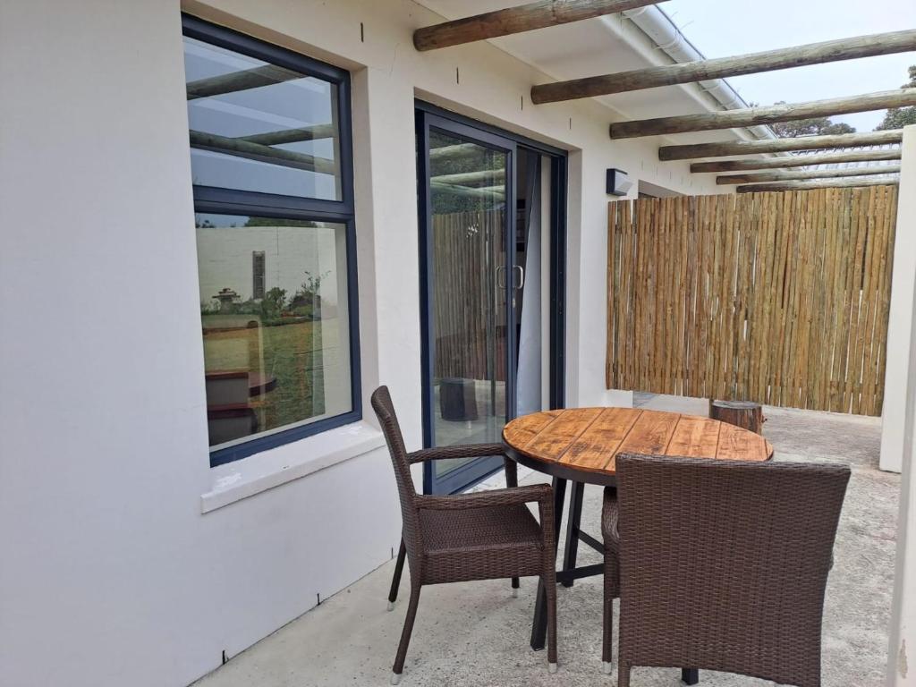 a patio with a table and chairs and a window at 5 Ysterklip Close, Hermanus in Hermanus