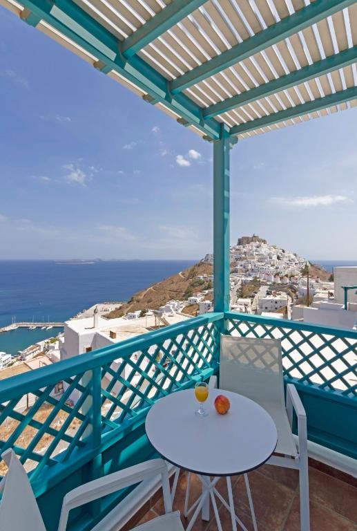 a balcony with a table and chairs and the ocean at Astypalaia Hotel Palace in Astypalaia