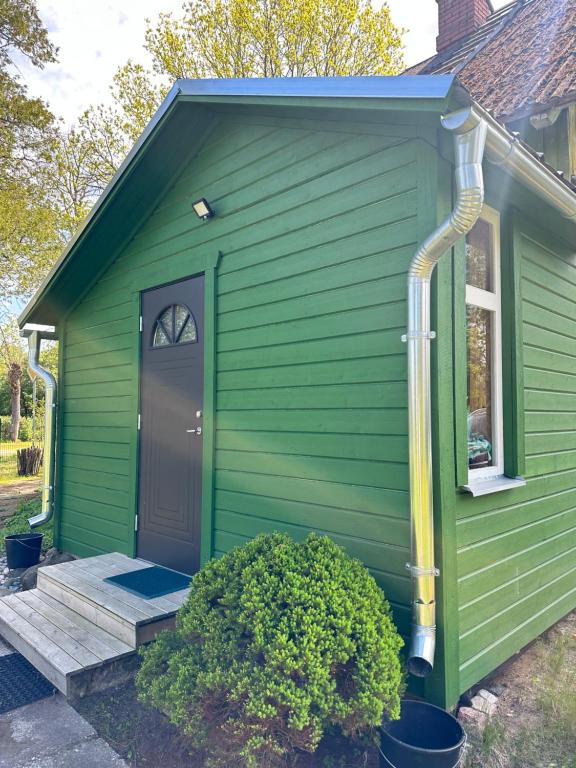 a green house with a green door and a porch at Bruno māja in Strenči