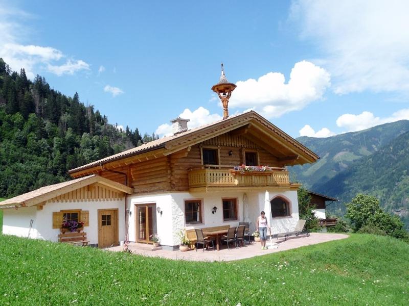 Eine Frau steht vor einem Haus auf einem Hügel. in der Unterkunft Chalet Schröckgut in Bad Hofgastein