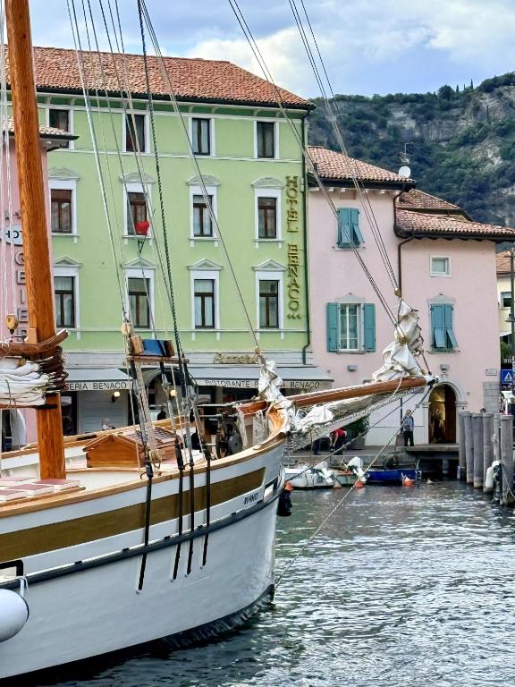 a boat in the water in front of buildings at Lake Hotel Benaco in Nago-Torbole