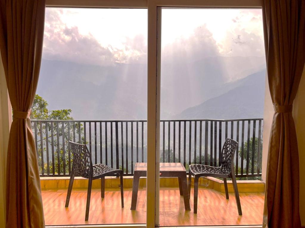 a balcony with a table and two chairs and a window at Happy Homestay Sittong in Mangpu