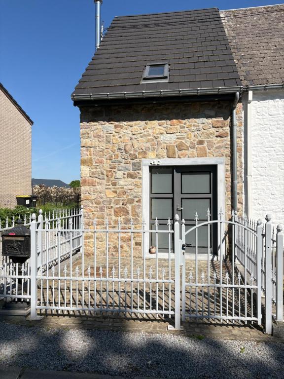 a white fence in front of a building with a door at Le Menes in Andenne