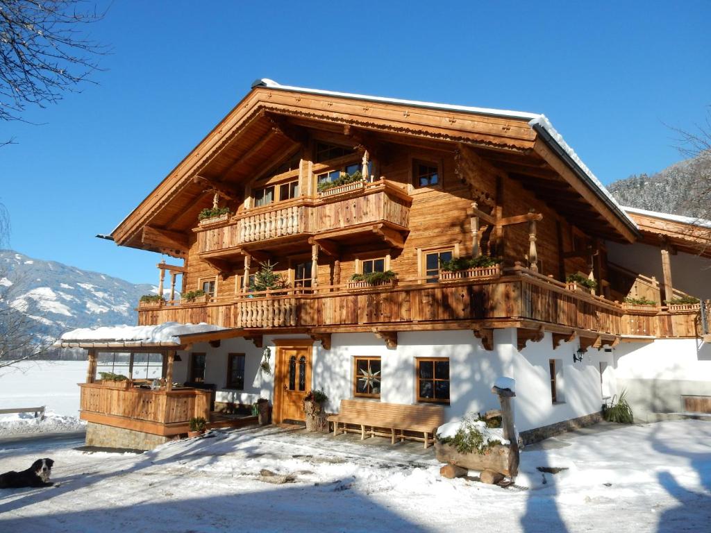 a large wooden house with a balcony in the snow at Häuserhof in Stumm