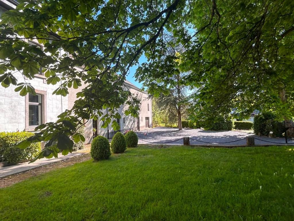 a house with a yard with green grass and trees at Le Clos des Marronniers in Léglise