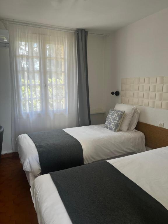 a hotel room with two beds and a window at Hôtel Castel Saint Anne in Le Castellet