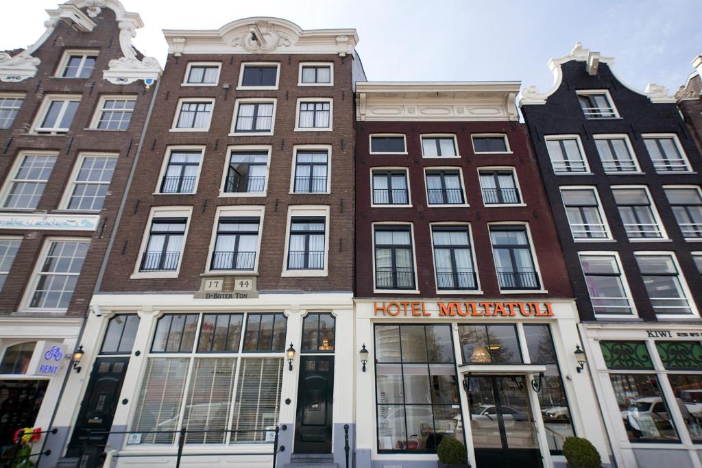 een groot bakstenen gebouw met een hotel ervoor bij Multatuli Hotel in Amsterdam