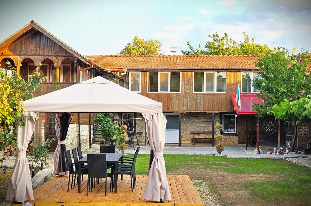 a table and chairs under a white umbrella in a yard at Вила ДАР in Gara Oreshets