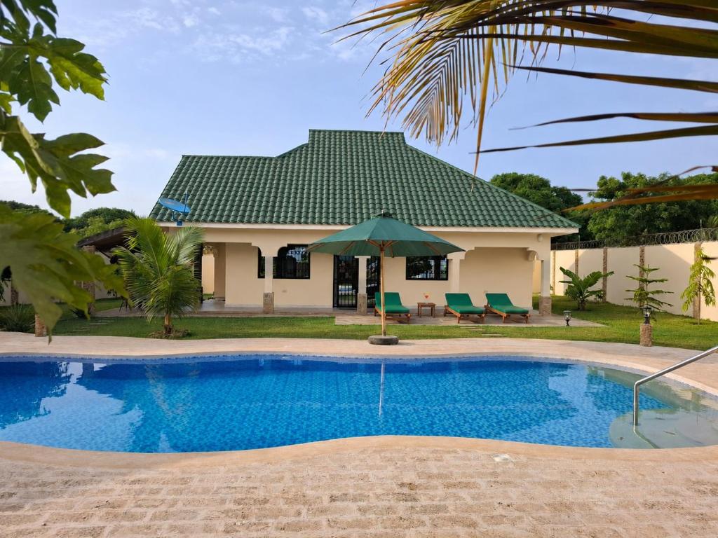 a villa with a swimming pool in front of a house at Ferienhaus Vacation Villa Diani Beach in Kinondo