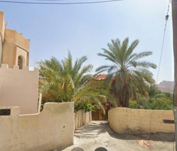 a street with palm trees and a building at Saal house in Nizwa