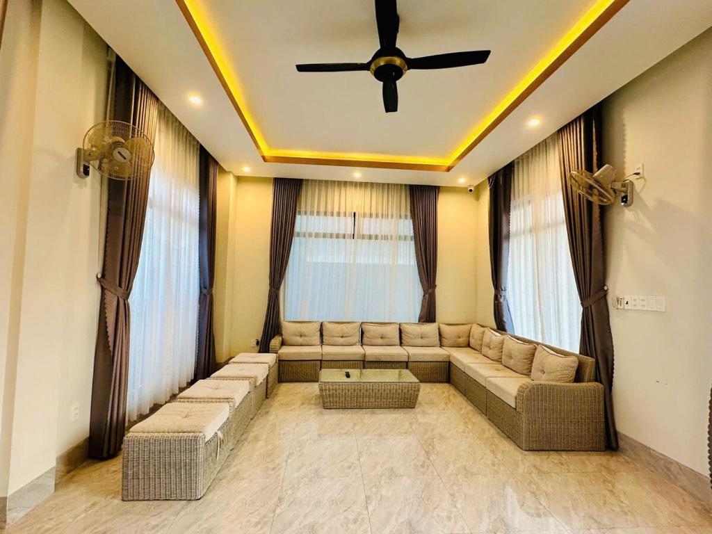 a living room with a couch and a ceiling fan at Arden Reserve Villa in Binh Thai