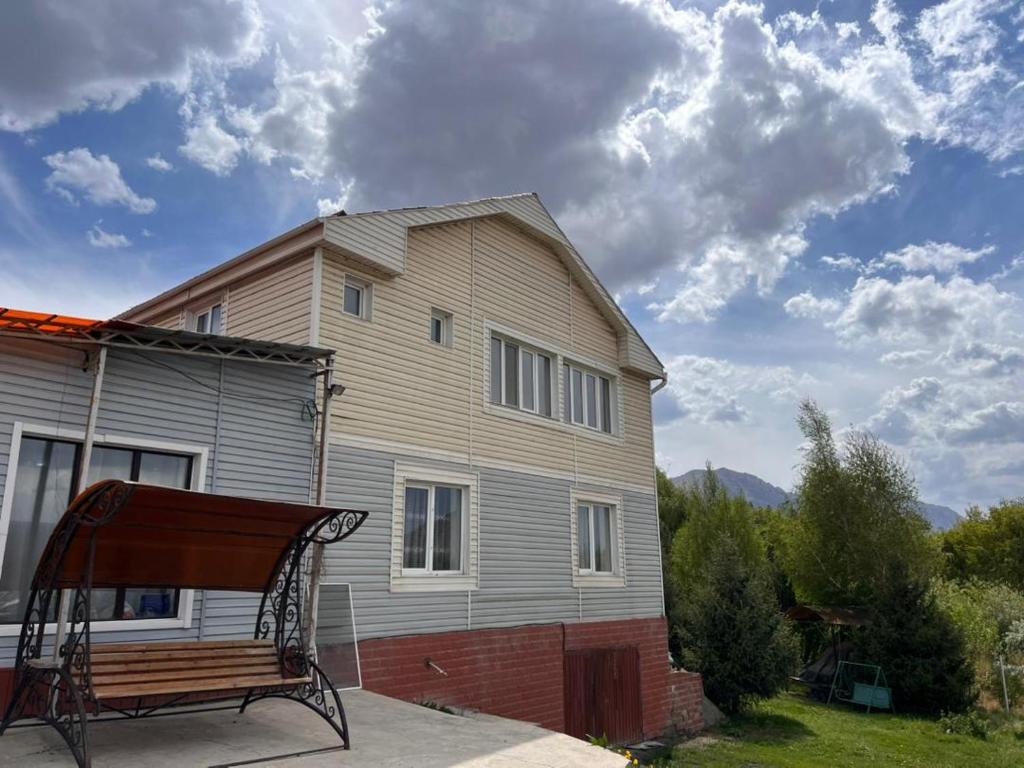 a house with a bench in front of it at AJO Guesthouse in Naryn