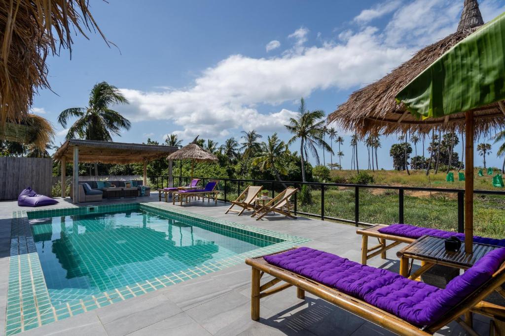 a swimming pool with purple lounge chairs and a resort at Manao Seaview Pool Villa 33 - 5 Mins Walk To The Beach in Ko Lanta