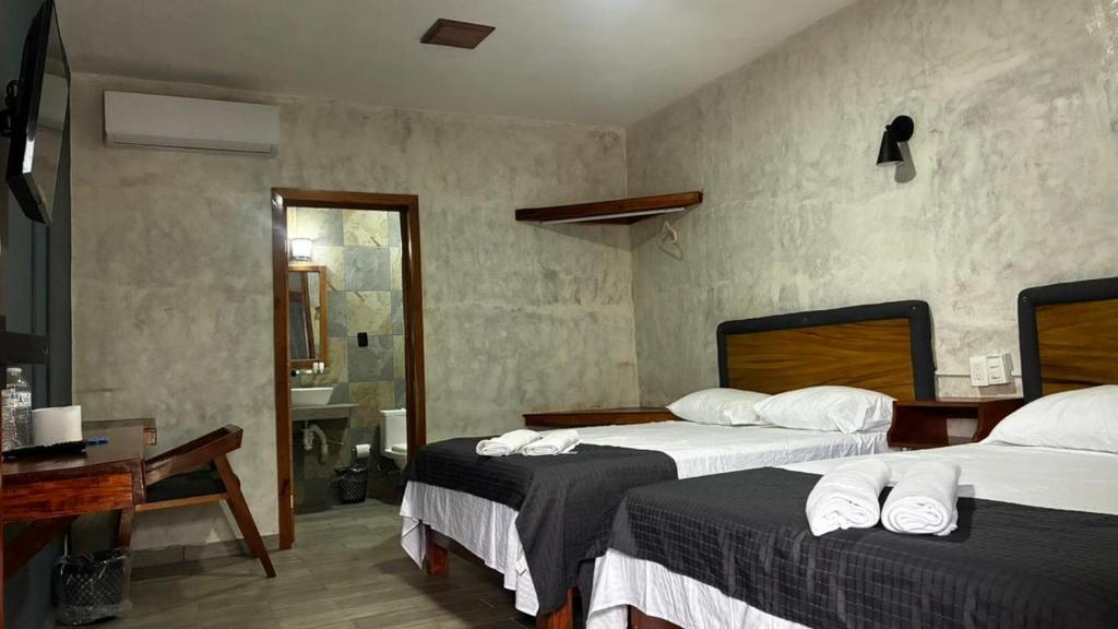 a hotel room with two beds and a desk at Villa Acuario in Tapachula