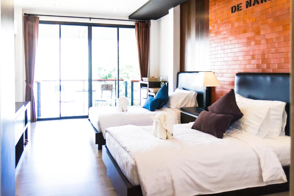 ein Hotelzimmer mit 3 Betten und einem großen Fenster in der Unterkunft Hotel De Nara-SHA Extra Plus in Chiang Mai