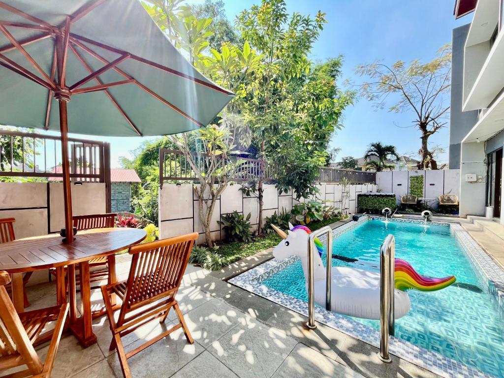 a backyard with a swimming pool with a table and an umbrella at MP Villa Tirta Sevil S3 Malang in Mantaak
