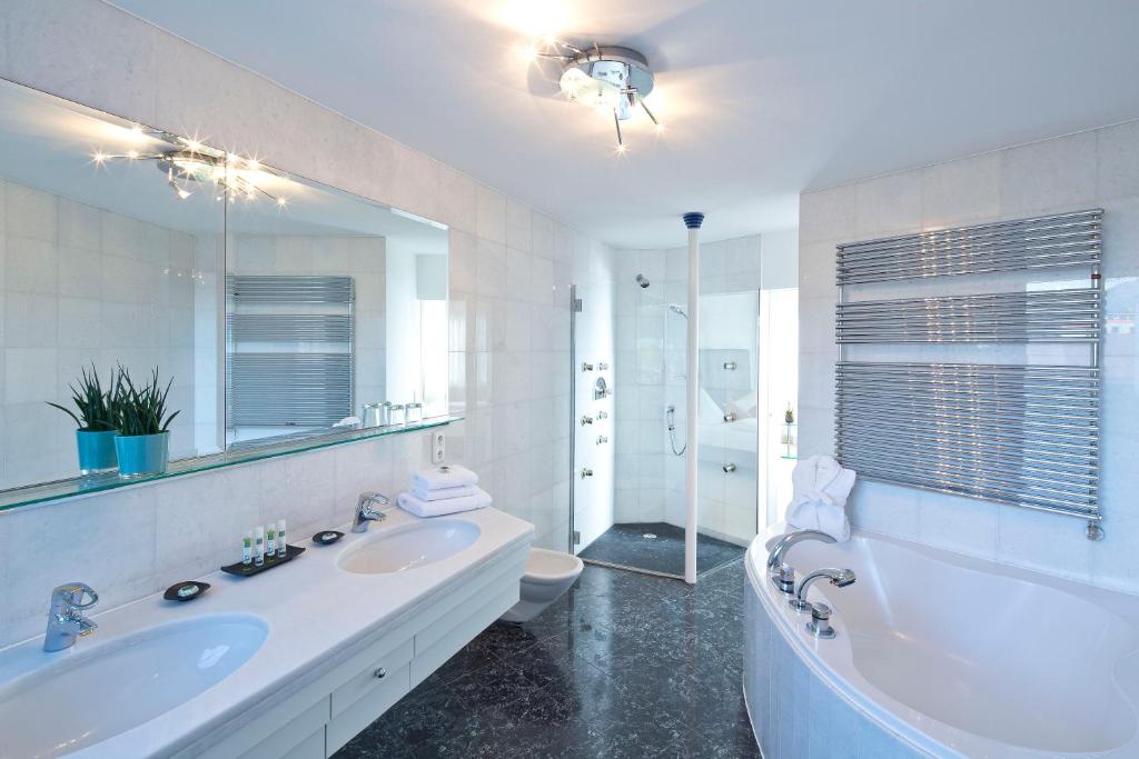 a bathroom with a tub and a sink and a toilet at Hotel Penz West in Innsbruck