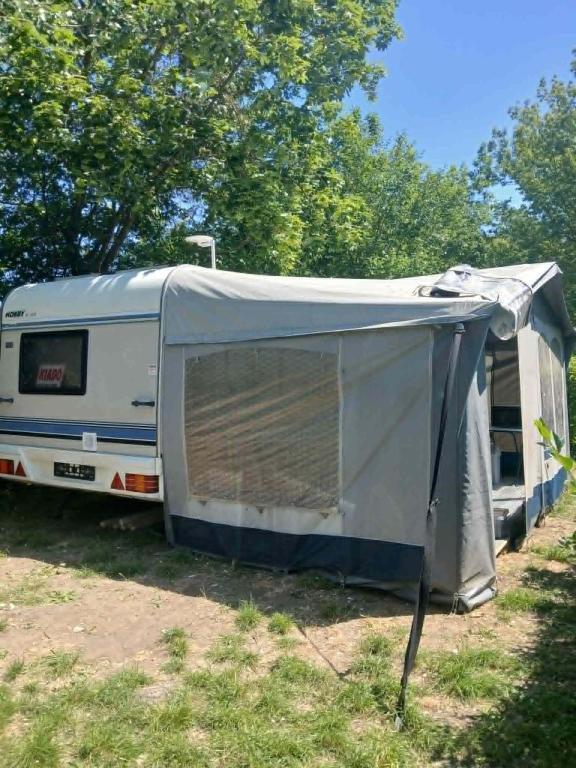 a trailer parked in a field next to trees at Túrkeve Lakó in Túrkeve